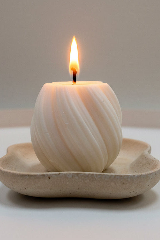 Candle in a shell holder on a white surface